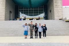 Brinda, Chadani, Javeria, and Zainab salute with a visiting soldier in front of the War Memorial of Korea Museum